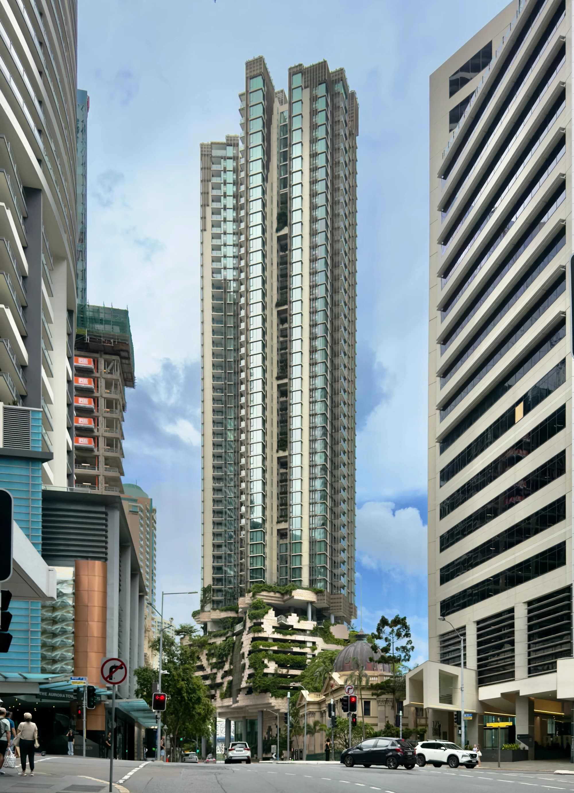 443 Queen Street rises above the street in Brisbane, with planted openings between vertical residential volumes.