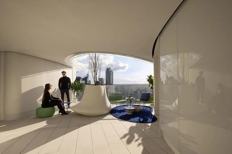 People sit in an open residential breezeway at The Butterfly, with a large framed opening towards Vancouver.