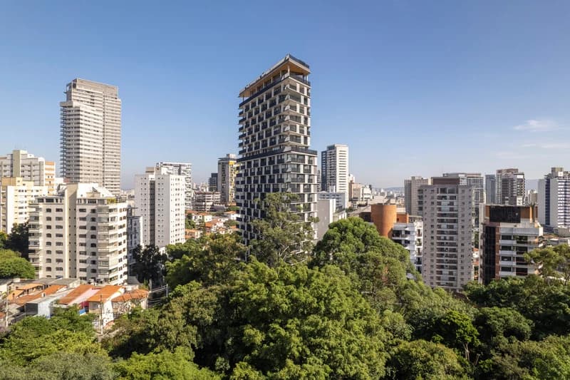 Onze22 stands above trees and neighbouring residential buildings in São Paulo.
