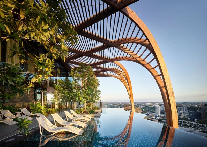 Upper House pool terrace beneath a timber pergola, overlooking Brisbane.