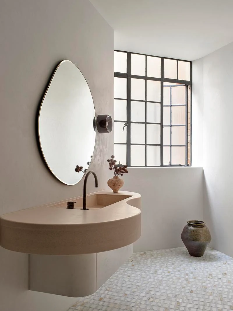 Curved bathroom basin beneath an irregular mirror · Anson Smart · via v2com